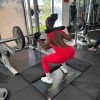 Rear view of a woman performing a barbell squat in the red Allure open-back jumpsuit, demonstrating its squat-proof durability.